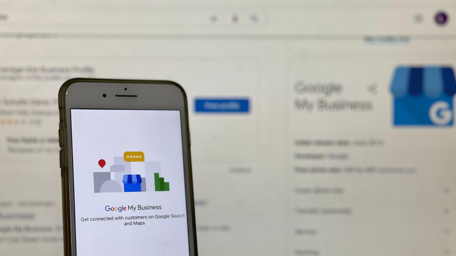 google my business mobile app on a phone with the computer screen in the background